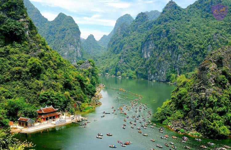 Tourists sitting on rowing boats enjoy the beautiful scenery in Trang An Landcape Complex, Ninh Binh province.