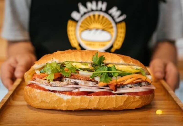 Close-up of traditional Vietnamese baguette filled with pate, meat and vegetables.