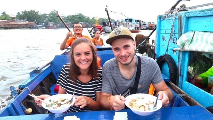 Visitors trying local food at floating markets in the early morning