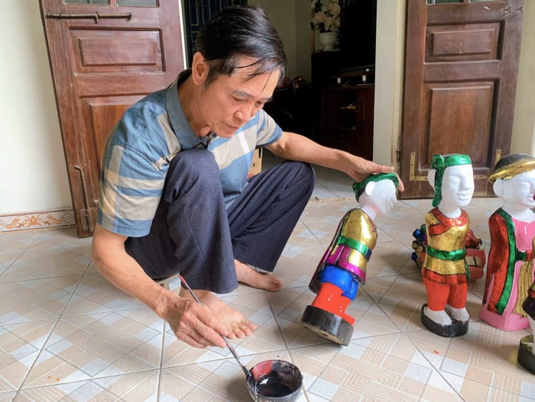 The skilled artisan Phan Van Manh is meticulously painting each puppet, bringing them to life with vibrant colors.